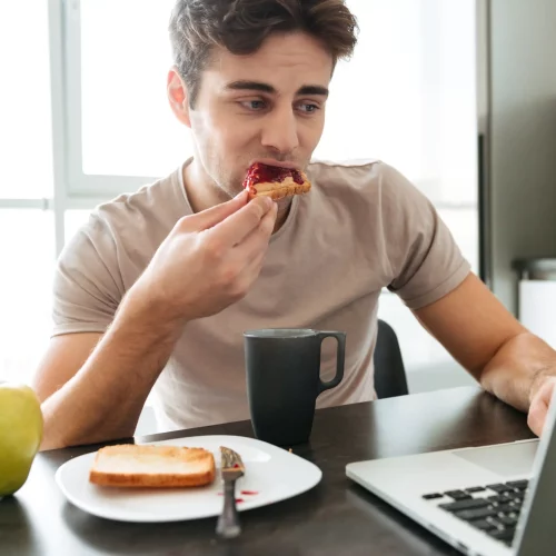 homem-atraente-concentrado-usando-laptop-enquanto-tomando-cafe-da-manha.opti