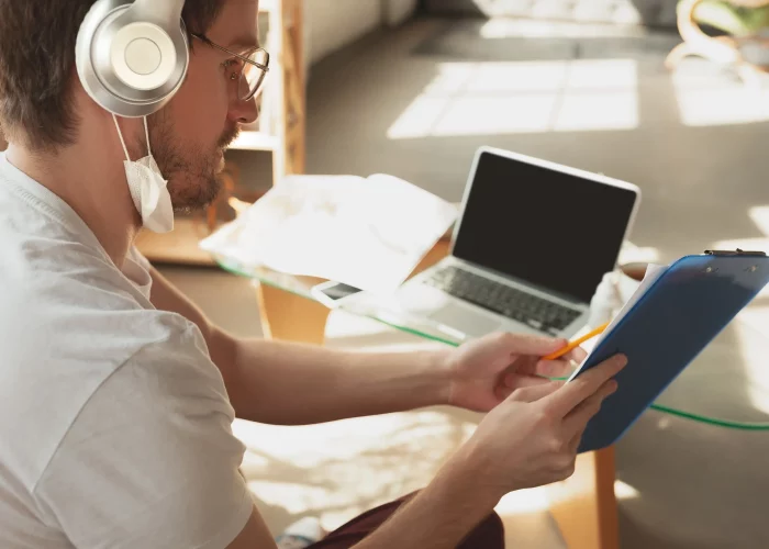 jovem-estudando-em-casa-durante-cursos-online-para-operario-jornalista-desenvolvedor-usando-laptop-smartphone-fones-de-ouvido.opti