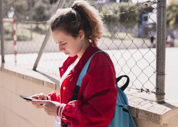 jovem-garota-digitando-texto-no-smartphone-perto-de-sportsground